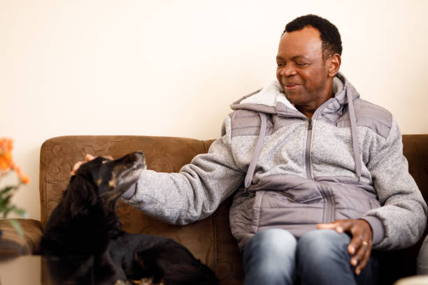 istock Senior man petting a dog at sofa 1284315922