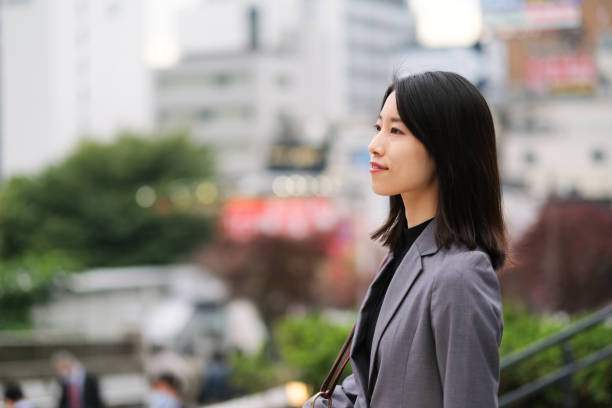 Profile view of Asian young woman on street in downtown Profile view of Asian young businesswoman on street in downtown shinjuku ward photos stock pictures, royalty-free photos & images