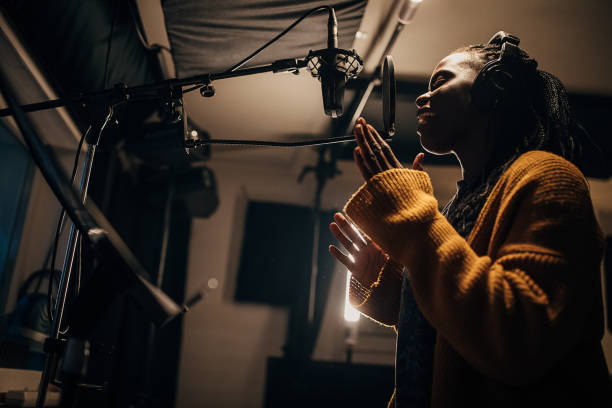 istock Black female singer singing into microphone in recording studio 1284317665