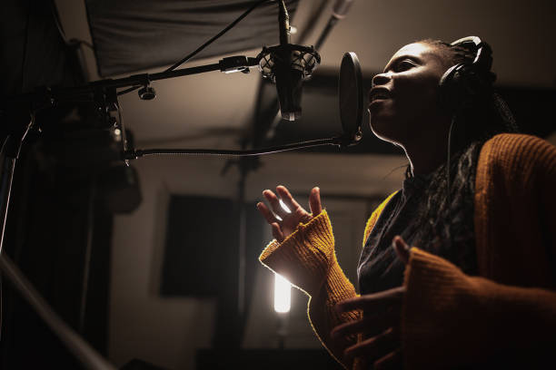 istock Black female singer singing into microphone in recording studio 1284317685