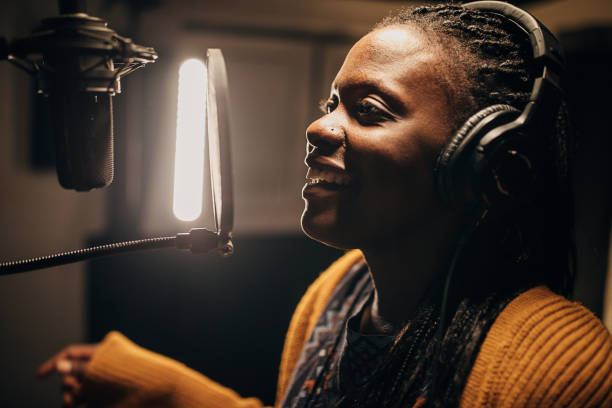 istock Black female singer singing into microphone in recording studio 1284317694