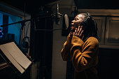 Black female singer singing into microphone in recording studio
