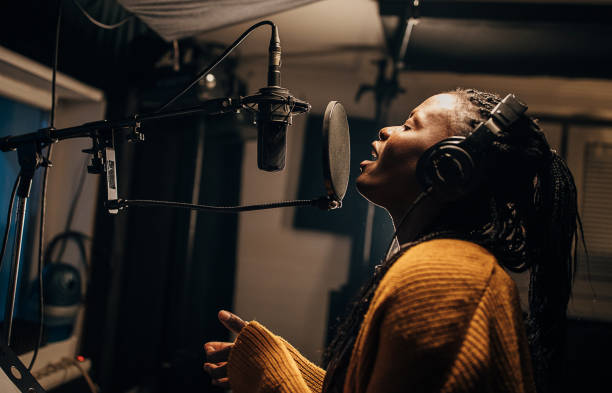 istock Black female singer singing into microphone in recording studio 1284317741
