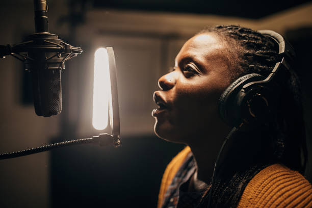 istock Black female singer singing into microphone in recording studio 1284317762