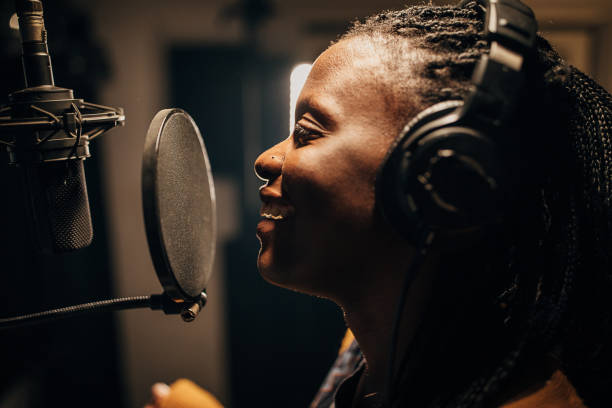 istock Black female singer singing into microphone in recording studio 1284317824