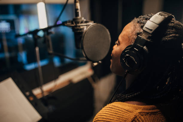 istock Black female singer singing into microphone in recording studio 1284318373