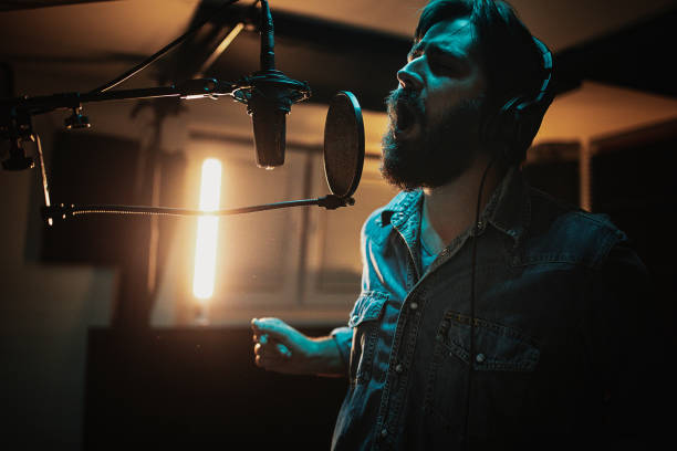 istock Male singer singing into microphone in recording studio 1284318656