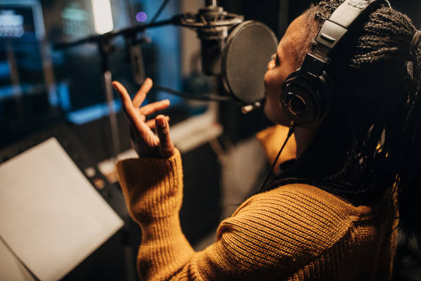 istock Black female singer singing into microphone in recording studio 1284318675