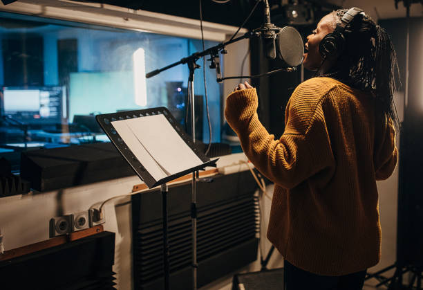 istock Black female singer singing into microphone in recording studio 1284318679