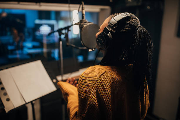 istock Black female singer singing into microphone in recording studio 1284318744