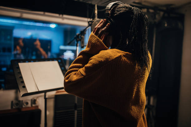 istock Black female singer singing into microphone in recording studio 1284319440