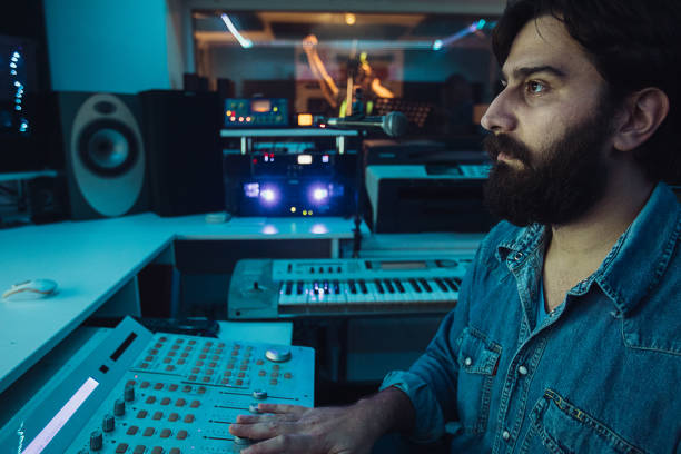 istock Male sound engineer working while male punker singer singing into microphone in recording studio 1284319508