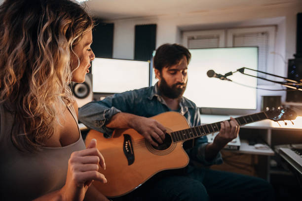 istock Young man playing acoustic guitar while woman singing in the professional studio 1284319529