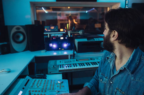 istock Male sound engineer working while male punker singer singing into microphone in recording studio 1284319628