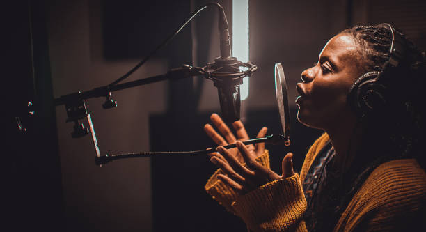 istock Black female singer singing into microphone in recording studio 1284319634