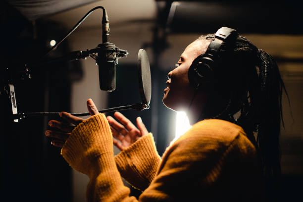 istock Black female singer singing into microphone in recording studio 1284319663