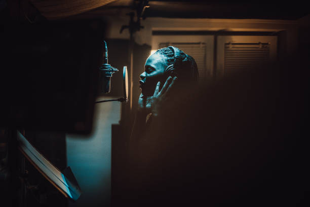 Black female singer singing into microphone in recording studio