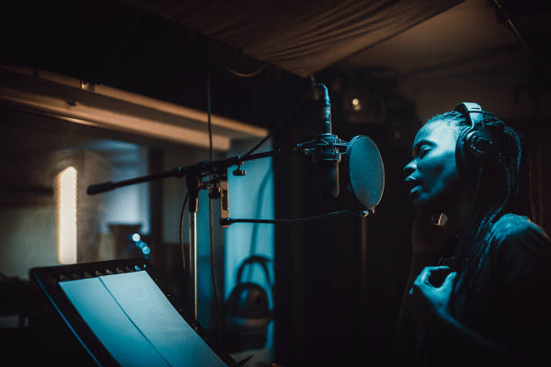 istock Black female singer singing into microphone in recording studio 1284319702