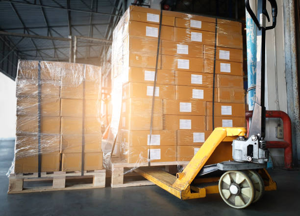 istock Cargo boxes, Shipment. Stack of cardboard boxes with hand pallet truck at the warehouse storage. Manufacturing and warehousing. 1284331565