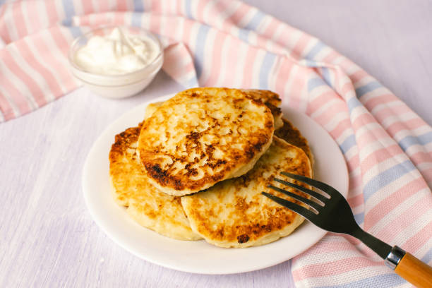istock Cottage cheese pancakes with sour cream on white background, breakfast or lunch 1284340375