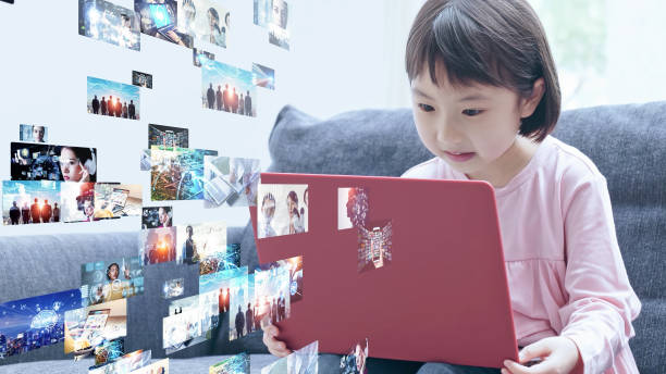 ノートパソコンでビデオを見てアジアの小さな女の子。デジタルコンテンツ。ソーシャルネットワーキングサービス。ストリーミングビデオ。通信ネットワーク。 - 子ども　動画 ストックフォトと画像