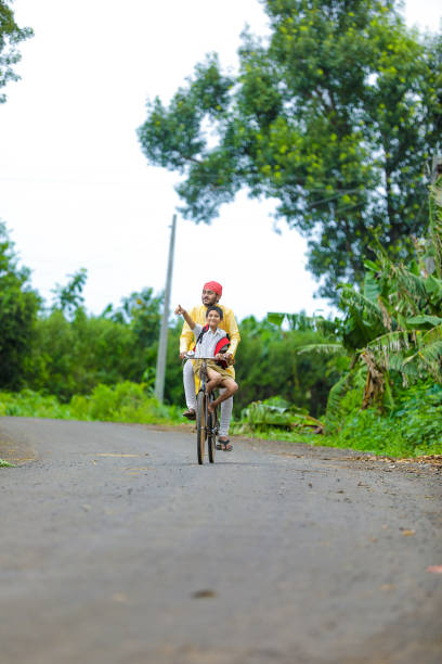 istock Young indian farmer and his son going to school on cycle 1284345054