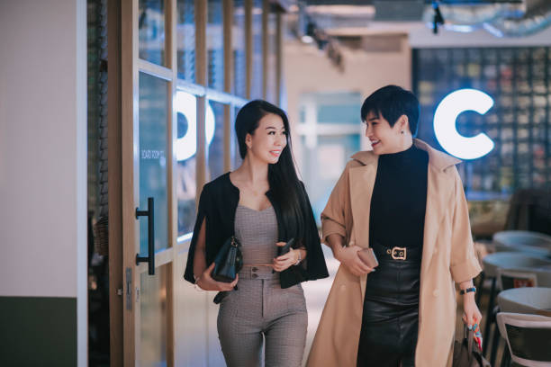 2 erfolgreiche asiatische chinesische geschäftsfrauen gehen glücklich ins büro - female healthy lifestyle wellbeing elegance stock-fotos und bilder
