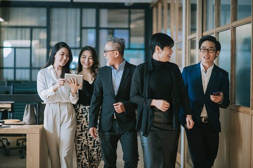 group of asian chinese successful office management team having discussion while walking toward camera