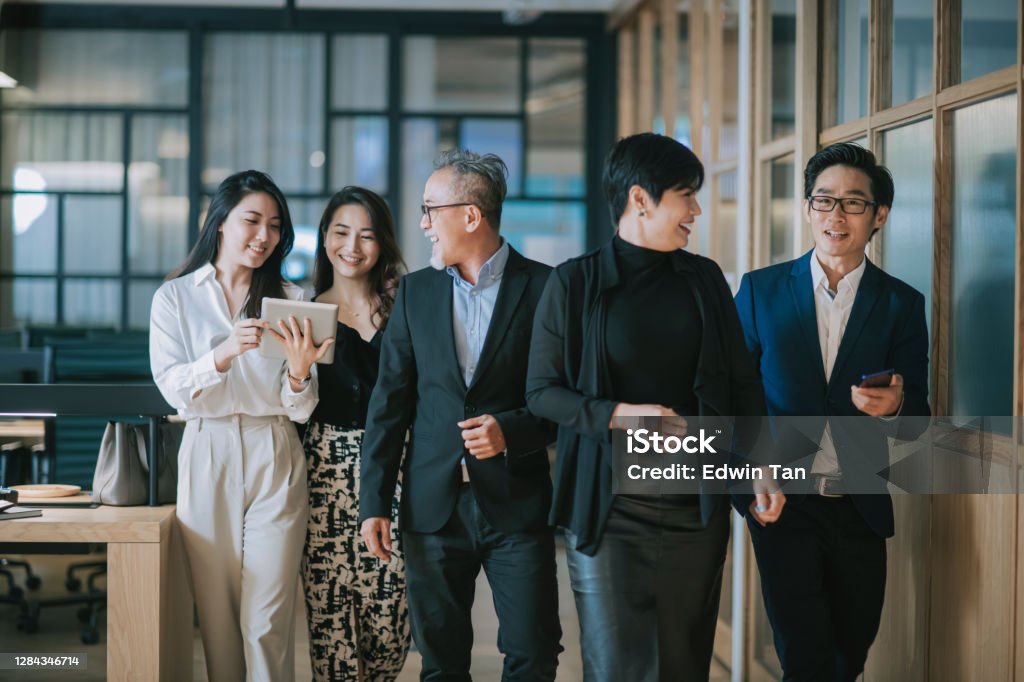group of asian chinese successful office management team having discussion while walking toward camera Business Stock Photo