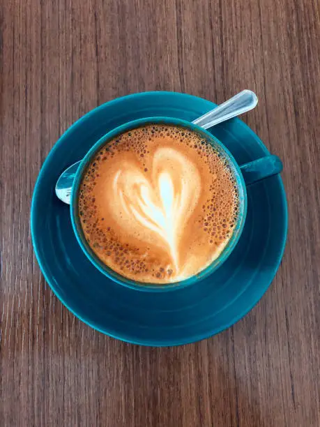 Heartshaped flatwhite pour in a blue saucer