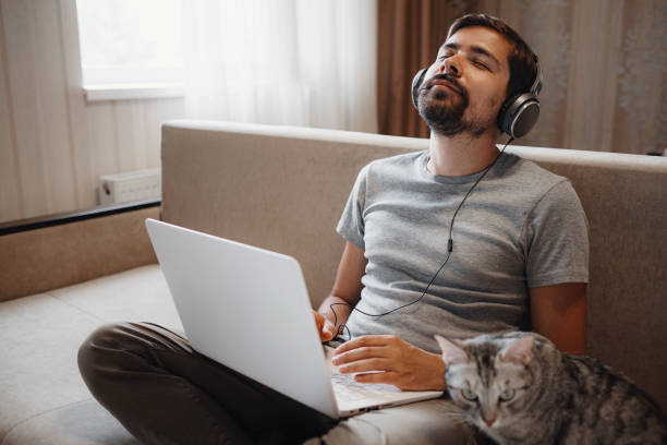 istock Man on sofa with headphones and notebook at home 1284351141