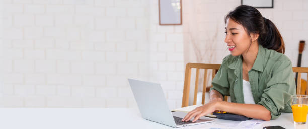 Asian woman use laptop and calculator calculate working project budget in kitchen at home Asian woman use laptop and calculator calculate working project budget in kitchen at home personal loan stock pictures, royalty-free photos & images