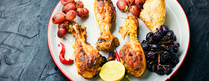 Baked chicken legs with grapes. Roasted chicken legs on plate