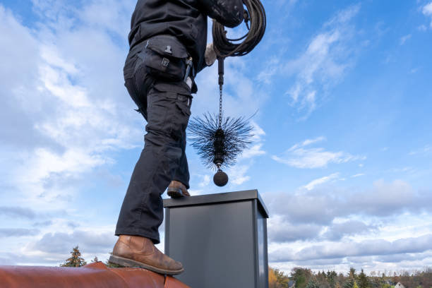 chimney sweep with stovepipe hat upon the roof Chimney sweep cleaning a chimney standing on the house roof, lowering equipment down the flue chimney photos stock pictures, royalty-free photos & images