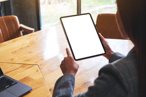 istock a woman holding and pointing finger at digital tablet with blank white desktop screen 1284360139