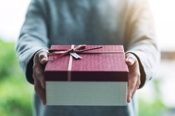 istock a woman holding and giving a red gift box 1284360141