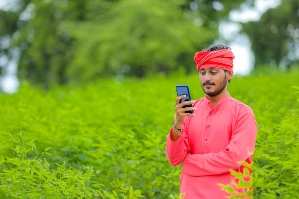 istock Young indian farmer using smartphone at green field 1284362010