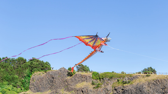A Dragon Kite fly in the blue sky over mountains
