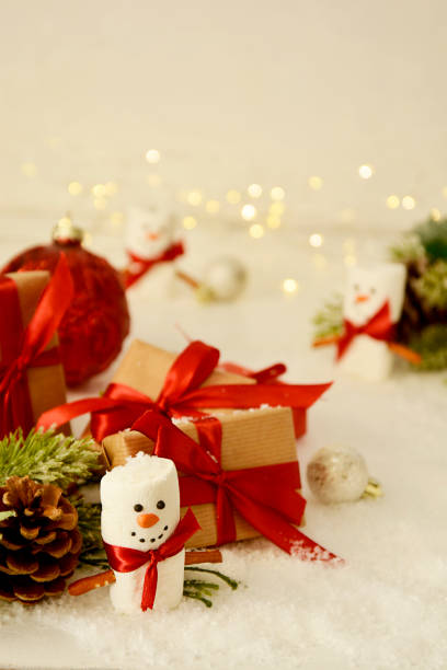 istock Christmas background. Gift boxes, marshmallow snow man, winter decorations, snow and bokeh lights. 1284366612