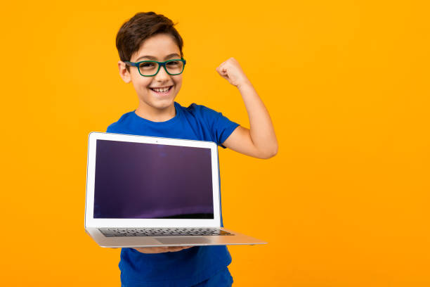 istock joyful caucasian boy shows laptop screen with mockup on yellow studio background with copy space 1284368341