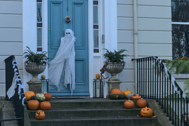 Spooky and beautiful Halloween decoration with many pumpkins, burning candle on the stairs and ghost on the door. Spooky and scary Halloween 2020 decoration, Dun Laoghaire, Dublin, Ireland stock photo