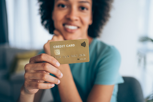 Beautiful young african-american woman holding a credit card - focus on foreground.