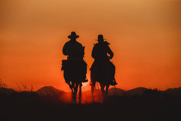 Silhouette the cowboy riding on a mountain with an yellow sky. stock photo