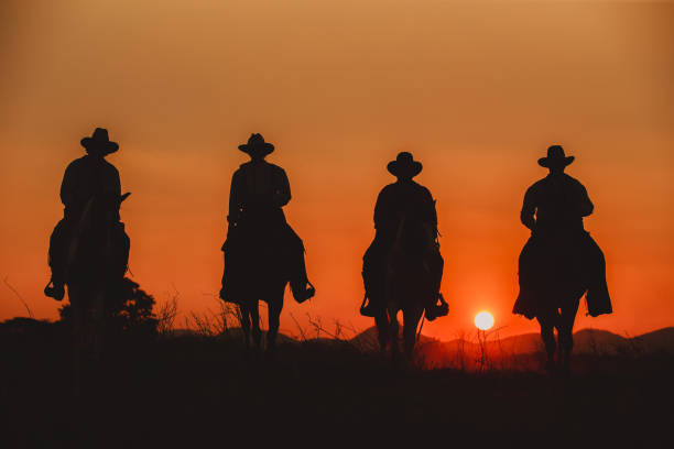 sylwetka kowboja jadącego na górze z żółtym niebem. - cowboy horseback riding nature blue zdjęcia i obrazy z banku zdjęć