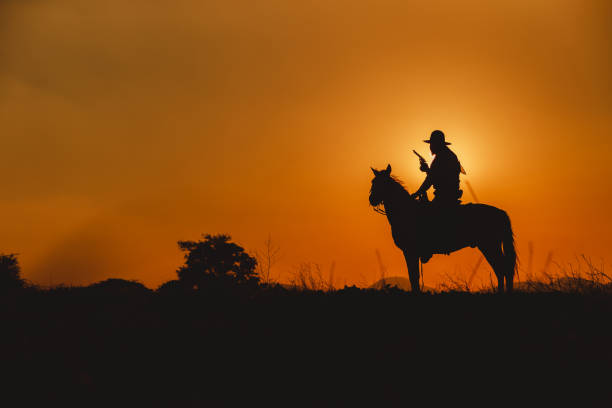 istock Silhouette the cowboy riding on a mountain with an yellow sky. 1284370113