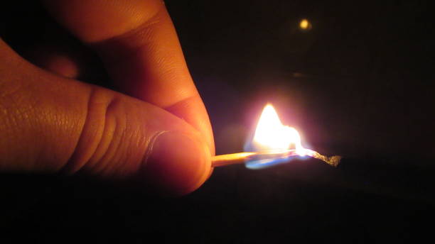 istock Close up of a man's hand lighting a single match in the dark 1284372011
