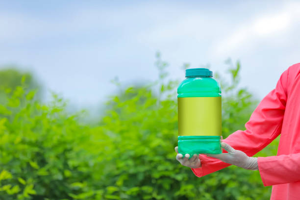 Young indian farmer showing fertilizer bottle at green field