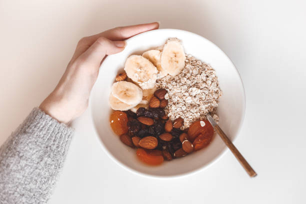 kohlenhydrat gesundes frühstück. haferflocken mit getrockneten früchten auf einem weißen teller. blick von oben - oatmeal porridge oat raisin stock-fotos und bilder