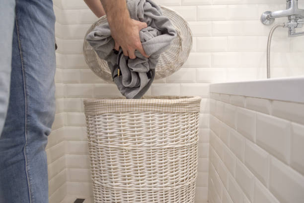 Man puts used dirty clothes in a dirty laundry basket.