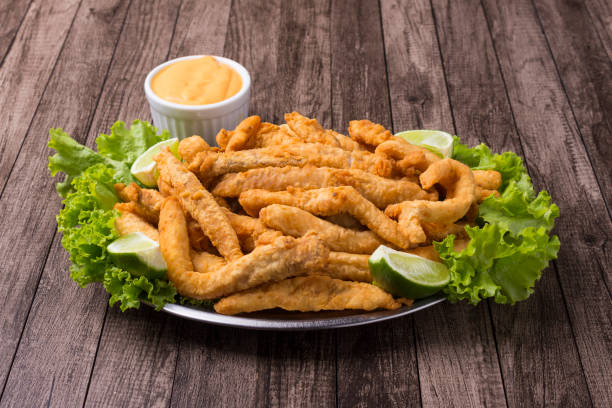 fotografía gourmet de porciones y pescado frito empanado servido en hojas de lechuga con limones y salsa tártara para acompañar. - quick cookies fotografías e imágenes de stock